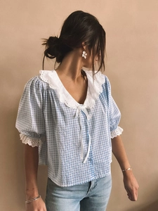 Close-up of blue plaid blouse with white lace collar and bow tie detail