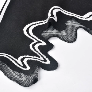 Detalle de vestido de punto negro con rayas blancas en contraste y dobladillo ondulado