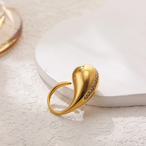 Macro shot of gold teardrop ring with sparkling cubic zirconia on a white stone base
