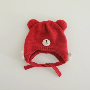 Detailaufnahme einer roten Baby-Strickmütze mit Bärenohren und weißen Flügel-Applikationen