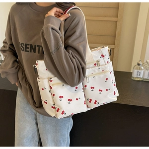 Detailed side view of white cherry print tote bag with multiple zippers on a model