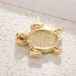 Detail of gold-plated turtle pendant base showing hollow grid texture for DIY jewelry