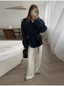 Trench corto blu scuro con cintura e revers abbinato a pantaloni bianchi larghi