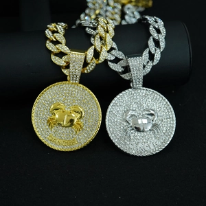 Close-up of gold and silver Cancer zodiac pendants with iced-out cuban chains