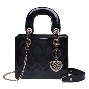 Close-up of black patent leather handbag featuring diamond quilting and heart charm