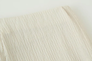 Macro shot of cream-white fabric showing unique crinkle texture on V-neck long-sleeve set