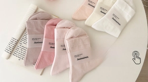 Detailansicht von fünf pastellfarbenen Socken mit Papierbanderolen auf weißem Tisch