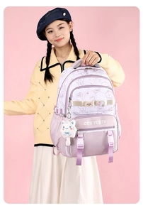 Detail of cute purple backpack with teddy bear prints and plush cat charm accessory