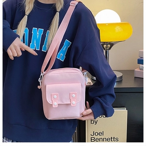 Close-up of pink canvas crossbody bag with dual buttons and adjustable shoulder strap