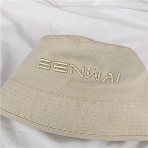 Detailed view of beige canvas bucket hat featuring SENWAI letter embroidery