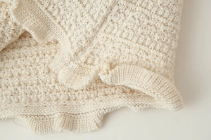 Vue détaillée de la texture du tricot crème et de l'ourlet à volants élégant