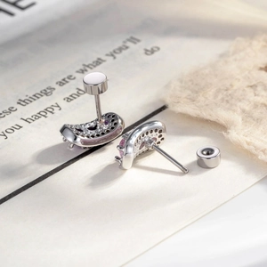 Silver curved stud earrings with pink and clear crystals on a minimalist background