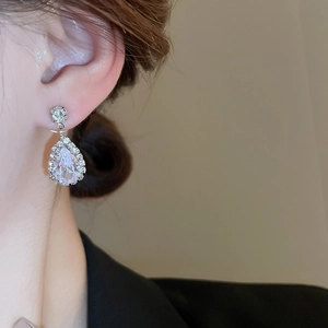 Close-up of sparkling teardrop rhinestone earring worn by a model in silver finish