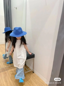 Dettaglio di un bambino con cappello di paglia blu, top bianco e jeans a zampa denim