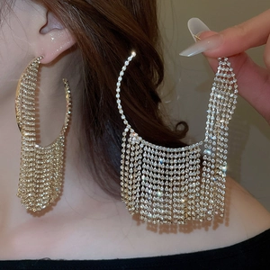 Detail of oversized gold tassel earrings with shimmering crystals on a model