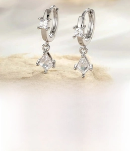 Macro view of silver geometric hoop earrings with square and kite-cut zircons details