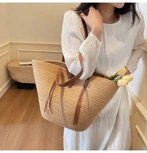 Lifestyle shot of large woven beach tote bag with brown leather straps and floral decor