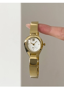 Detailed view of the gold bangle watch featuring a minimalist white dial and metal texture