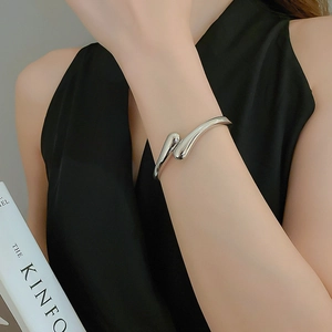 Detail of silver streamlined open bangle with high-polished metallic mirror finish