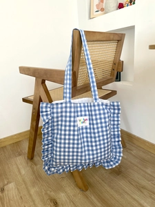 Detailed view of blue checkered cotton tote with ruffle trim and fun fun party label