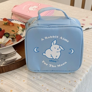 Close-up of blue and pink rabbit pouches with metal zippers on floral cloth