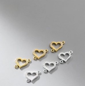 Macro shot of double-hole heart connectors for DIY jewelry making in gold and silver