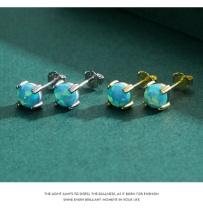 Macro shot of silver and gold S925 sterling silver opal stud earrings on a green background