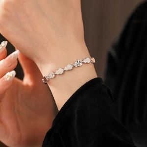 Macro view of silver heart and disc chain link bracelet worn on a female wrist