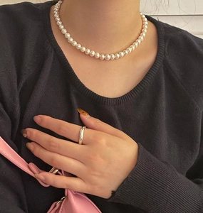 Elegant 10mm white pearl necklace and minimalist silver ring worn on black knitwear