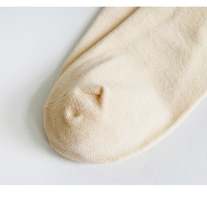 Macro shot showing fine knitted texture and toe detail of beige cotton socks for women