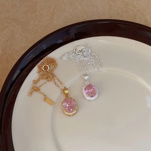 Close-up of pink oval zircon necklaces in gold and silver finish with halo setting