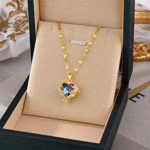 Golden heart pendant necklace with blue-purple gemstone in a green jewelry box