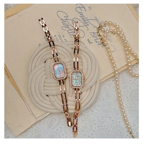 Detail showing two rose gold rectangular quartz watches with shell dial and pearl necklace