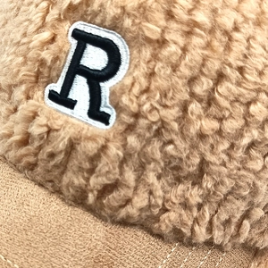 Détail de la broderie lettre R sur une casquette en polaire marron et daim