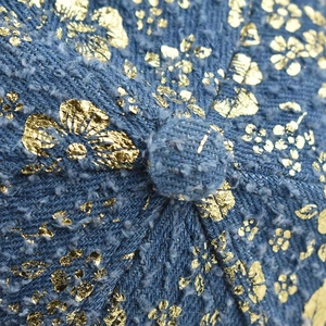 Detailed macro view of blue tweed fabric texture with gold foil floral print and top button