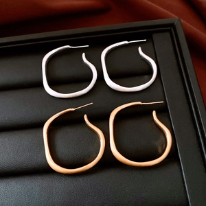 Detailed view of irregular twisted gold and silver stud earrings on a jewelry display tray
