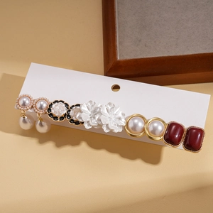 Détails de boucles d'oreilles en perles et fleurs en résine sur fond vintage crème