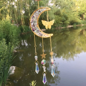 Detail of golden moon sun catcher with multi-color crystals and butterfly pendant outdoors