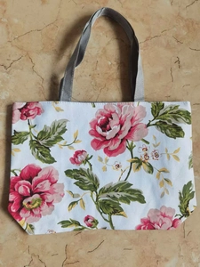 Detail of floral canvas tote bag featuring realistic pink rose prints and grey handles