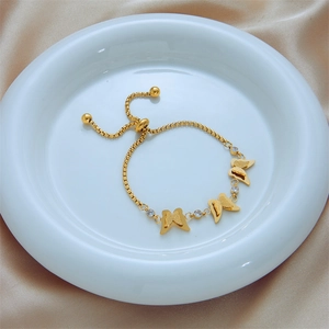 Adjustable gold butterfly chain bracelet with sparkling zircon charms on a silk surface