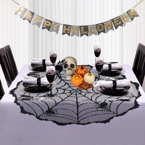 Detail of black lace spider web table runner with Happy Halloween banner and pumpkins