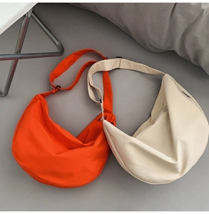 Detail view of orange and off-white crescent nylon crossbody bags with adjustable straps