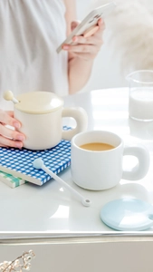 Detail of round ceramic mugs with cream and blue lids and a blue sphere stirrer