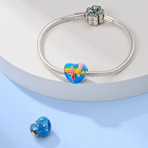 Detail of silver snake chain bracelet featuring heart charms with starry enamel design