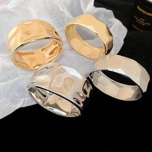 Detailed view of silver and gold irregular geometric metal bangles on a dark background