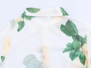 Gros plan détaillé d'une blouse blanche avec motifs de feuilles vertes et fleurs jaunes