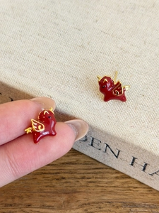 Detail of red enamel horse stud earrings with gold plating and silver needle backing