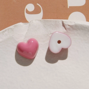 Close-up of pink and white resin heart beads with precise drill holes for DIY jewelry