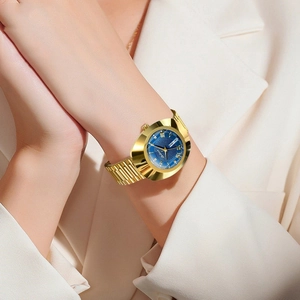 Detail of a women's gold watch with blue sunray dial and faceted crystal on wrist