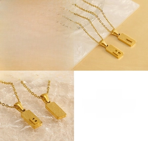 Close-up of gold stainless steel rectangular pendants with matte finish and letter engraving